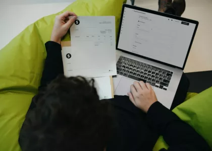 A person sitting on a bean bag chair working on a laptop