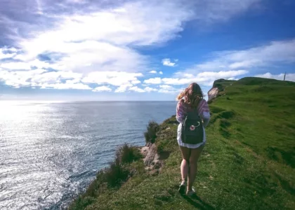 woman standing on cliff near body of water during daytime