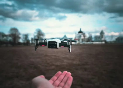 white and black drone flying over the field during daytime