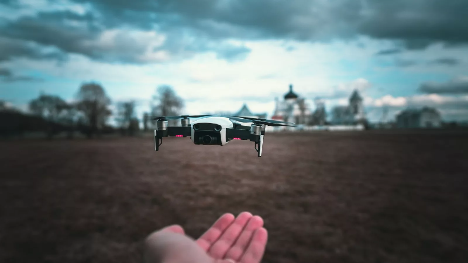 white and black drone flying over the field during daytime